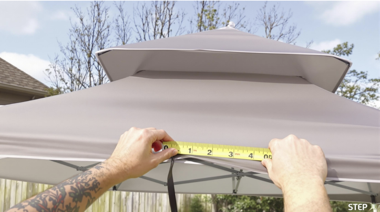 man measuring the length of a gazebo tent frame with yellow measuring tape 